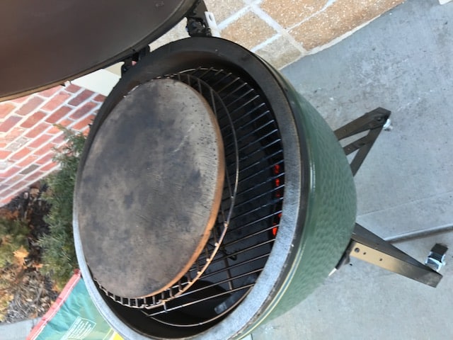 big green egg open with baking stone on it